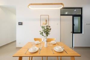 a wooden table with plates and bowls and a vase with flowers at Muji Home Lavile KL Sunway Velocity 双威永乐城中文房东Pool in Kuala Lumpur