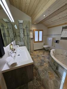 a bathroom with a sink and a tub and a toilet at Chalet Familial Sublime in Crans-Montana