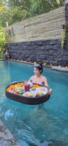 Ubud Harmony Private Villa and Pool في أوبود: وجود امرأة جالسة على طاولة في حمام السباحة