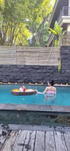Ubud Harmony Private Villa and Pool في أوبود: وجود امرأة في مسبح في فناء خلفي