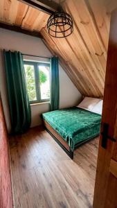 Un dormitorio con una cama verde y una ventana en Dadajowa Osada - Dadaj en Biskupiec