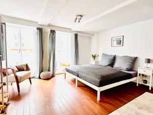 a white bedroom with a bed and a chair at Die Stader Sehnsucht in Stade
