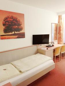 a room with a bed and a desk with a computer at Hotel Igel in Püchersreuth