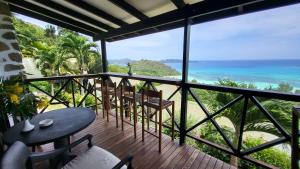 einen Balkon mit einem Tisch, Stühlen und Meerblick in der Unterkunft Mango Lodge in Anse Volbert Village