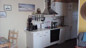 eine kleine Küche mit weißen Schränken und einem Herd in der Unterkunft Ferienwohnung im Schwedenhaus in Ueckermünde + 20 Fotos