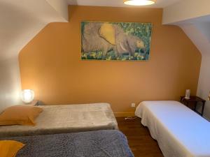 a bedroom with two beds and a painting on the wall at Les Amis de Beauval in Seigy