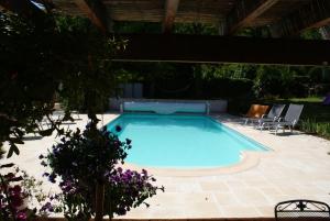 una piscina en un patio con sillas alrededor en Le Jardin des Roches, en Moigny