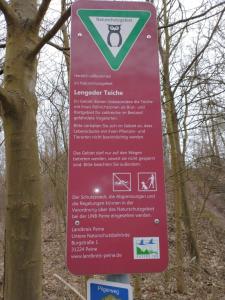 a sign on a tree in the woods at Apartment an den Teichen in Lengede