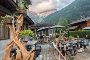 een patio met tafels en stoelen met bergen op de achtergrond bij Eden Hotel, Apartments and Chalet Chamonix Les Praz in Chamonix-Mont-Blanc