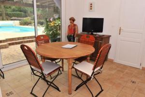 mesa con sillas y TV en una habitación en GITE LES ROCHES, en Moigny