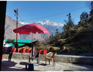 a red umbrella sitting next to a table and chairs at Nk Brothers Homestay, Joshimath in Joshīmath