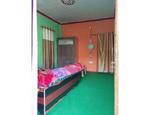 a room with a bed and a green floor at Nk Brothers Homestay, Joshimath in Joshīmath