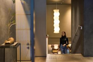 a woman walking down the stairs in a lobby with lights at Hotel Resol Kyoto Shijo Muromachi in Kyoto