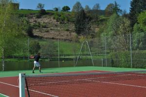 un hombre está jugando al tenis en una pista de tenis en Bungalow 3 étoiles - eeiidb, en Matour
