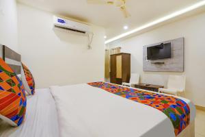 um quarto com uma cama branca e uma televisão em FabHotel Ambika Elite em Vijayawada