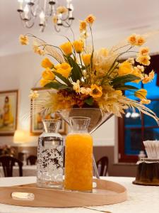 un jarrón de flores amarillas y un vaso de zumo de naranja en Hotel Delalut, en Ravne na Koroškem