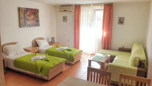 a room with two beds and a table and a couch at Guesthouse Tri Palme in Becici