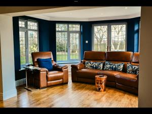 a living room with a leather couch and chairs at Brackenborough Lakes Resort in Louth