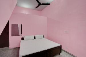 um quarto com uma cama numa parede cor-de-rosa em OYO Hotel star palace em Noida