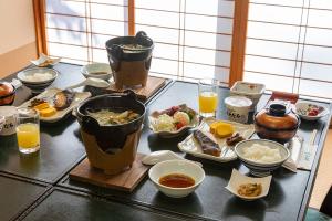 静かなお宿加賀美 في Shimojo mura: طاولة مع مجموعة من الطعام وكؤوس من عصير البرتقال