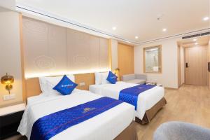 una habitación de hotel con 2 camas y una silla en Sunshine Apartment Hotel en Móng Cái