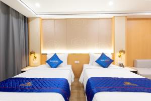 two beds in a hotel room with blue pillows at Sunshine Apartment Hotel in Móng Cái