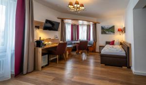 ein Hotelzimmer mit Schreibtisch, Bett und Tisch in der Unterkunft Hotel Weißbräu in Oberhaching