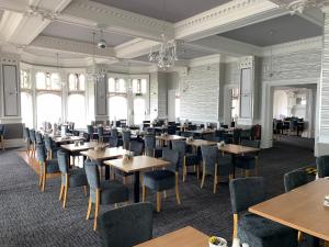 a dining room with tables and chairs and windows at Hotel De Paris in Cromer