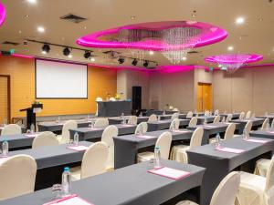 una sala de conferencias con mesas y sillas y una pantalla de proyección en VELA Dhi GLOW Pratunam en Bangkok