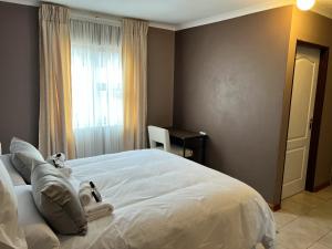 Schlafzimmer mit einem weißen Bett, einem Schreibtisch und einem Fenster in der Unterkunft Mapalesa Guest House in Mohales Hoek