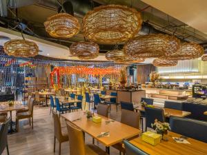 VELA Dhi GLOW Pratunam في بانكوك: مطعم به طاولات وكراسي وثريات