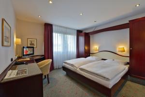 a hotel room with a large bed and a desk at Hotel Imperial in Cologne