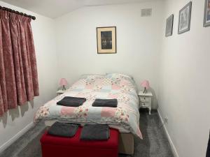 een slaapkamer met een bed en een rode poef bij Lovely 1 bedroom flat in quiet Wimbledon in Londen
