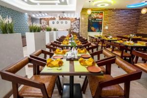 un comedor con mesas y sillas con comida en Rainbow Tower Hotel Airport Road en Hyderabad