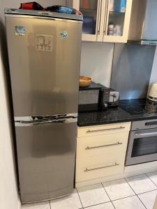 een roestvrijstalen koelkast in een keuken naast een fornuis bij Lovely 1 bedroom flat in quiet Wimbledon in Londen