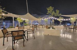 un patio con mesas, sillas y luces por la noche en Seogwipo The Hotel en Seogwipo