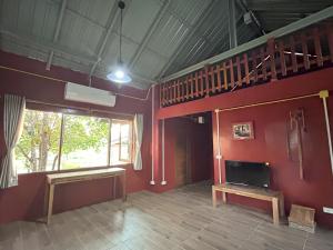 a living room with red walls and a stair case at Teak@Teak in Ban Cha-om