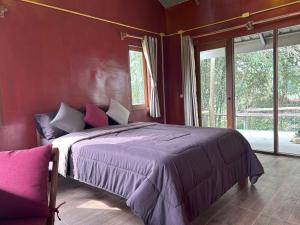 a bedroom with a large bed in a red wall at Teak@Teak in Ban Cha-om