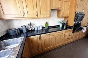 a kitchen with wooden cabinets and a sink at Green Haven Villa - 4BR Spacious House with Hot tub, Ample Parking, Air Condition, WIFI, Netflix, Patio & Garden in Oxford