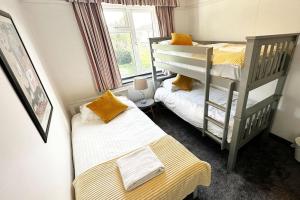 a bedroom with two bunk beds and a window at Green Haven Villa - 4BR Spacious House with Hot tub, Ample Parking, Air Condition, WIFI, Netflix, Patio & Garden in Kidlington