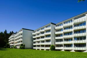 un gran edificio de apartamentos con un campo verde delante en DEKRA Congresshotel Wart, en Altensteig