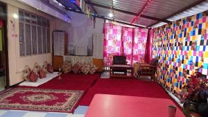 een kamer met rode vloerbedekking en kleurrijke muren bij Benus Darjeeling Home A Backpacker Hub in Darjeeling