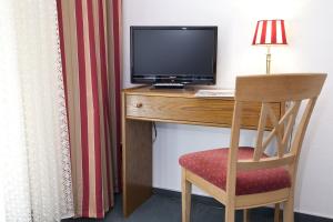 a room with a desk with a television and a chair at Bio-Hotel Upländer Hof in Willingen