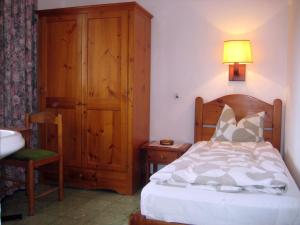a bedroom with a bed and a lamp and a chair at Pension Casa Austria in Calella