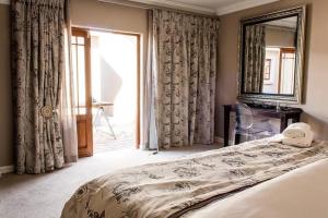 a bedroom with a bed and a mirror and a window at Kerala Hotel in Bloemfontein
