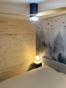 Le Nivolet, cosy appartement في شامبيري: غرفة نوم بسرير وجدار عليه طيور