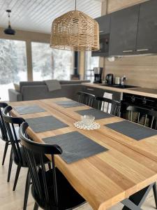 une cuisine avec une table en bois et des chaises noires dans l'établissement WALD Villas - Aavasaksa, Lapland, à Aavasaksa