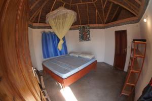 - une chambre avec un lit et un plafond en bois dans l'établissement AFLII Beach Club ( Zanzibar Beach ), à Mtwara