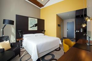 ein Hotelzimmer mit einem Bett, einem Tisch und Stühlen in der Unterkunft Sheraton Hannover Pelikan Hotel in Hannover