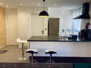 Le Nivolet, cosy appartement في شامبيري: مطبخ مع كرسيين بار ومكتب